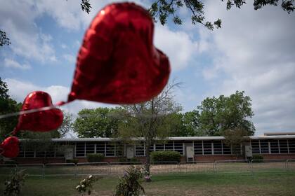 Algunos globos con forma de corazón decoran un monumento conmemorativo improvisado frente a la Escuela Primaria Robb el lunes 30 de mayo de 2022, en Uvalde, Texas. Diecinueve niños y dos maestras fueron asesinados por un joven armado en el plantel la semana pasada. (AP Foto/Wong Maye-E)