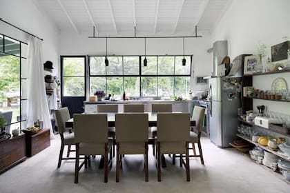 Una estantería de madera sobre el lateral completa el espacio de guardado y enmarca la zona de comedor, con mesa de madera comprada hace treinta años en La Lucila y sillas tapizadas (Fernando Moy).
