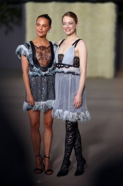 Alicia Vikander y Emma Stone coincidieron con propuestas de vestidos cortos en gris y negro con plumas de Louis Vuitton. Stone apostó por combinar el suyo con medias fantasía en tono negro.