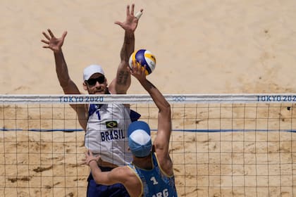 Alison Cerutti, de Brasil, bloquea contra Nicolas Capogrosso, durante un partido de voleibol de playa masculino en los Juegos Olímpicos de Verano de 2020, el sábado 24 de julio de 2021, en Tokio, Japón.