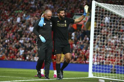 Alisson Becker deja el campo de Anfield Road; por la lesión, no disputará este miércoles la Supercopa europea contra Chelsea.