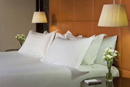 Almohadas bien mullidas y luces puntuales junto a la cama en una de las suites de NH Collection Lancaster