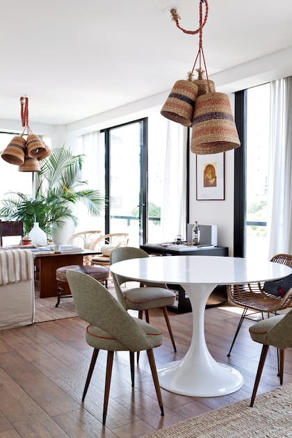 Alrededor de la mesa ‘Tulip’, sillón de ratán (ambos comprados por Mercado Libre) y sillas americanas (Soy Mi Casa). Idea de Justina Socas, la lámpara de canastos fue lo primero que mandaron a hacer.
