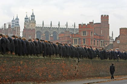 Alumnos de Eton observan atentamente, trepados en el muro perimetral del colegio, el tradicional wall game, un exclusivo juego de la escuela que combina rugby con fútbol.