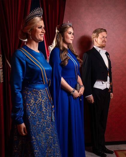 Amalia se encuentra expuesta junto a las estatuas de cera de sus padres. La Reina lleva el vestido inspirado en el que lució durante la investidura del rey Guillermo en abril de 2013. Se trata de un elegante diseño de Jan Taminiau en color azul Klein de manga larga y falda con bordados en el bajo a juego con los puños. Y una inolvidable capa a juego. Como joyas, la tiara de zafiros, regalo del rey Guillermo III a su mujer, la reina Emma.