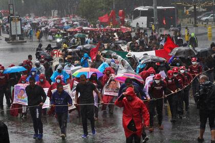 Amigos y parientes que buscan justicia para 43 estudiantes de la normal rural de Ayotzinapa que desaparecieron marchan bajo la lluvia durante una protesta, el viernes 26 de agosto de 2022, en la Ciudad de México. (AP Foto/Marco Ugarte)