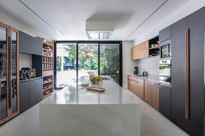 Amoblamiento en madera de incienso, cava con marcos de madera y vidrio, estación de café y alacenas con sistema ‘Servo Drive’ (Blum). Isla central en Dekton.