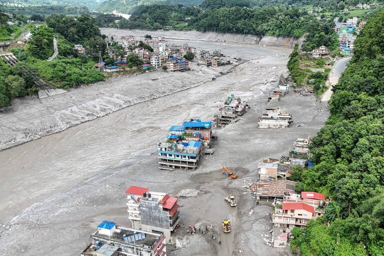 An aerial view shows houses lying deluged in sludge following flash floods in Trishuli of Nepal's Nuwakot district on August 27, 2026. Rescue teams scoured devastated zones August 27 for more than 1,300 people missing a day after flash floods and landslides along the Nepal-Tibet border killed at least 273, sweeping away entire villages. (Photo by Arun SANKAR / AFP)