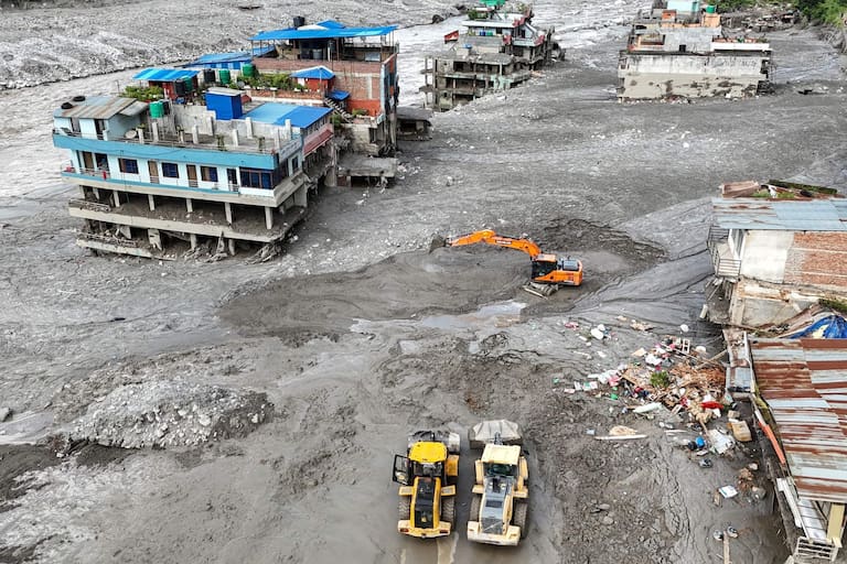 An aerial view shows workers using excavators to clear sludge following flash floods at Trishuli in Nepal's Nuwakot district on August 27, 2026. Rescue teams scoured devastated zones August 27 for more than 1,300 people missing a day after flash floods and landslides along the Nepal-Tibet border killed at least 273, sweeping away entire villages. (Photo by Arun SANKAR / AFP)