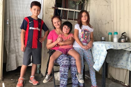 Analía con tres de sus nueve hijos, en la puerta de su casa en Burzaco
