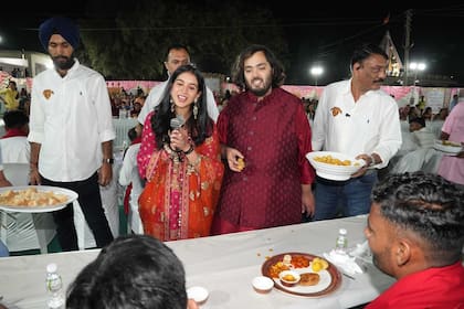 Anant Ambani y su novia Radhika Merchant, saludan a los aldeanos en la comida ofrecida a toda la comunidad local en las afueras de Jamnagar, Gujarat, India (Reliance group via AP)