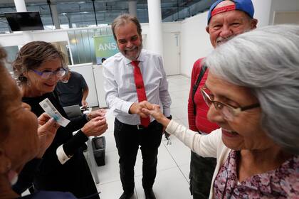 El defensor de la Tercera Edad, Eugenio Semino, junto a jubilados que se acercan a firmar