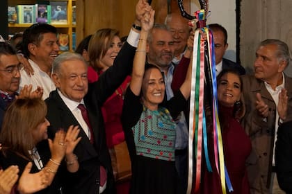 Andrés Manuel López Obrador levanta la mano de Claudia Sheinbaum durante una ceremonia para entregarle el bastón de mando del partido en la Ciudad de México