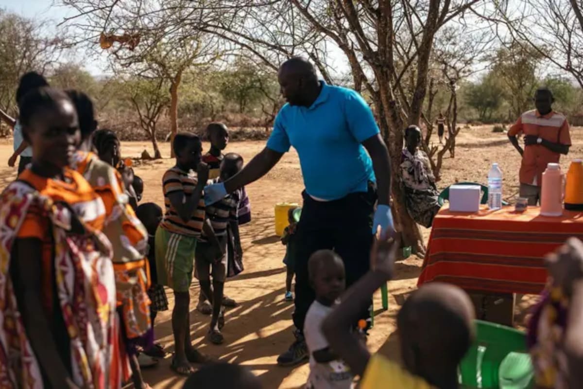 Andrew Ochieng examina a un grupo de personas en su clínica improvisada de leishmaniasis visceral, a la sombra de un árbol en Akorikeya