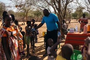 Andrew Ochieng examina a un grupo de personas en su clínica improvisada de leishmaniasis visceral, a la sombra de un árbol en Akorikeya