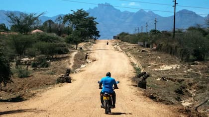 Andrew Ochieng se pone el casco y balancea las piernas sobre su fiel motocicleta