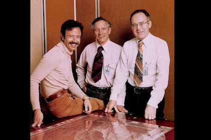 Andy Grove, Robert Noyce y Gordon Moore; según la Web de Intel, la foto es de 1978, pero sobre la mesa se ve el plano de un 8080, un microprocesador de 1974. Michael Malone aclara el punto en su libro "The Intel Trinity": la foto fue tomada en realidad en 1975. Para entonces, la compañía se había centrado en los microprocesadores, que habían inventado, sin demasiada pompa, en 1971