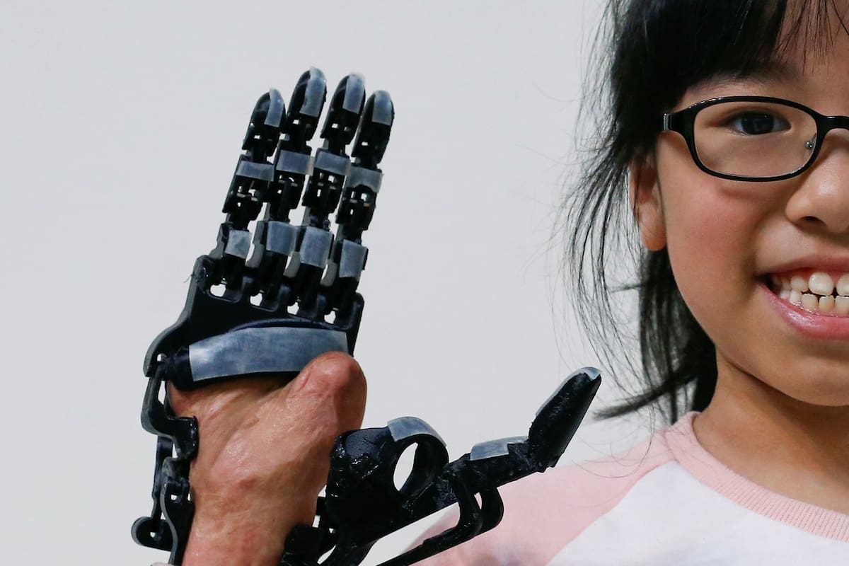 Angel Peng, de 8 años, posa para una fotografía con una mano impresa en 3D diseñada y construida por el ingeniero Chang Hsien-Liang, en Taoyuan, Taiwan.