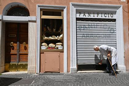 Angelo Arrigoni levanta la persiana de su panadería que, en pocos días, cerrará definitivamente. ¿Los motivos del cierre? Desde hace años, la zona de Borgo Pío se convirtió en un lugar exclusivo para turistas: la mayoría de los departamentos allí se alquilan para turistas y todos los locales apuntan a ese mercado. Angelo pidió a las autoridades municipales la autorización para transformar su panadería y convertirlo en café, con mesas en la vereda, pero fue rechazado. (Photo by Andreas SOLARO / AFP)