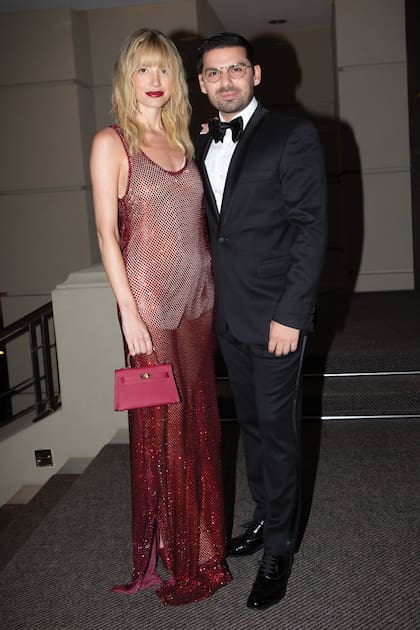 Angie Landaburu, con un look de impacto de Joti Harriague y minibolso Hermès, y Augusto Marini.