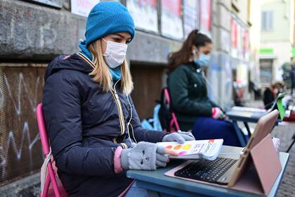 Anita Lacovelli y su amiga Lisa Rogliatti, ambas de 12 años, se sientan frente a la escuela Italo Calvino en Turín mientras protestan contra el cierre de escuelas debido a las restricciones por Covid-19, el 17 de noviembre de 2020