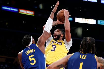 Anthony Davis (3), de los Lakers de Los Ángeles, lanza a canasta ante Kevon Looney (5), de los Warriors de Golden State, en la primera mitad del juego de la NBA que enfrentó a ambos equipos en Los Ángeles, el 19 de octubre de 2021. (AP Foto/Ringo H.W. Chiu)