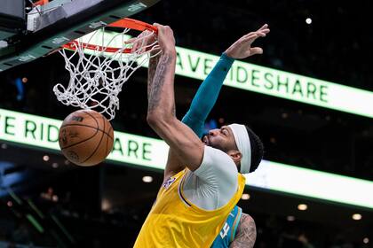 Anthony Davis, de los Lakers de Los Ángeles, clava el balón, mientras recibe una falta de Miles Bridges, de los Hornets de Charlotte, durante la segunda mitad del juego de baloncesto de la NBA, el lunes 5 de febrero de 2024, en Charlotte, Carolina del Norte. (AP Foto/Jacob Kupferman)
