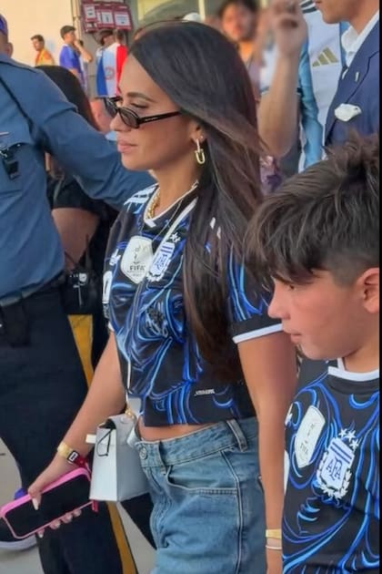 Antonela Roccuzzo –con jean, la camiseta suplente de Argentina y una Mini Kelly Hermès blanca– abandona el MetLife Stadium llevando de la mano a su hijo Mateo
