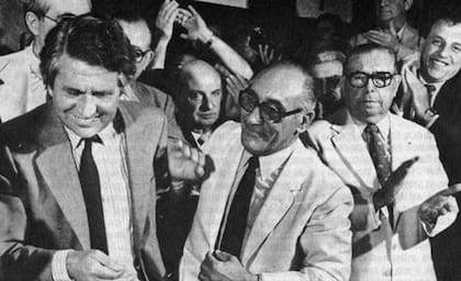 Antonio Alegre se saluda con Federico Polak, cuando después de una exitosa intervención de 40 días, el 5 de enero de 1985 el abogado le devolvió el club a los socios de Boca; sobre el margen derecho de la imagen aplaude Alberto J. Armando (Archivo)