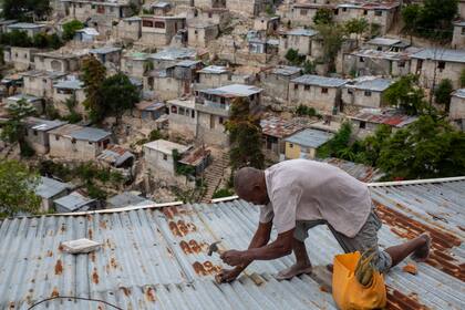 Antony Exilien trabaja para reforzar el techo de su vivienda en respuesta a la tormenta tropical Elsa, en Puerto Príncipe, Haití, el sábado 3 de julio de 2021. ( AP Foto/Joseph Odelyn)