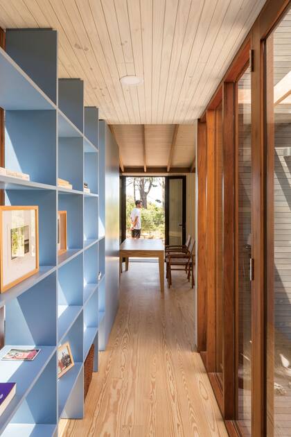 Apoyada sobre un ventanal que le da fondo transparente, una biblioteca de MDF laqueado vincula y unifica los dos cuerpos de esta casa en José Ignacio.