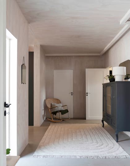 Aprovecharon el pasillo para crear un estar, con una silla mecedora (Ikea), alfombra (Ellos) y un aparador de factura propia.