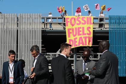 ARCHIVO - Activistas medioambientales de Extinction Rebellion sostienen una pancarta que dice "Combustibles fósiles-Muerte) mientras protestan en la Semana de la Energía de África, el 20 de octubre de 2022 en Ciudad del Cabo, Sudáfrica. (AP Foto/Nardus Engelbrecht, Archivo)