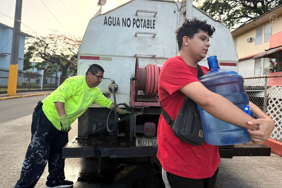 Archivo.- Bryan Pérez carga un bidón de agua de cinco galones hacia su apartamento en el complejo de vivienda pública Villa Kennedy, en San Juan, Puerto Rico, el 10 de junio de 2026