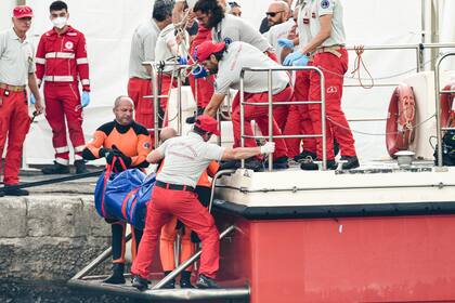 ARCHIVO - Buzos del Departamento de Bomberos de Italia llevan una bolsa de plástico con el cuerpo de una de las víctimas de un naufragio, en Porticello, Sicilia, en el sur de Italia, el jueves 22 de agosto de 2024. (AP Foto/Salvatore Cavalli, Archivo)