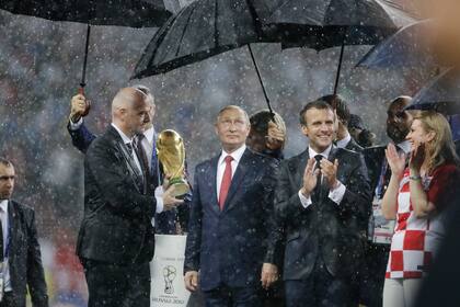 ARCHIVO - De izquierda a derecha, el presidente de la FIFA Gianni Infantino, el presidente ruso Vladimir Putin, el presidente francés Emmanuel Macron y la presidenta croata Kolinda Grabar-Kitarovic bajo la lluvia tras la final del Mundial de 2028 entre Francia y Croacia, el domingo 15 de julio de 2018, en Moscú. (AP Foto/Natacha Pisarenko)