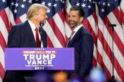 ARCHIVO - El candidato presidencial republicano, el expresidente Donald Trump, a la izquierda, mira a su hijo Donald Trump Jr. en una fiesta de observación de la noche electoral, el 6 de noviembre de 2024, en West Palm Beach, Florida. (AP foto/Alex Brandon, archivo)