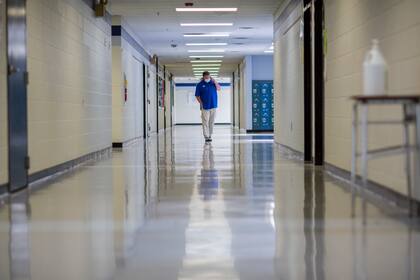 ARCHIVO - El director de una escuela secundaria camina por un pasillo vacío de la institución mientras habla con una de sus maestras para ver cómo sigue de sus síntomas de COVID-19, el viernes 20 de agosto de 2021, en Wrightsville, Georgia. (AP Foto/Stephen B. Morton, archivo)