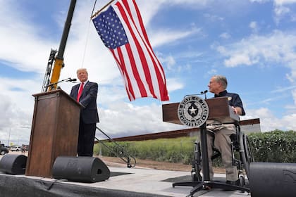 Archivo.- El gobernador de Texas, Greg Abbott, a la derecha, y el expresidente Donald Trump pronuncian discursos cerca de una sección del muro fronterizo en Pharr, Texas, el miércoles 30 de junio de 2021