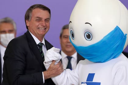 ARCHIVO - El presidente brasileño Jair Bolsonaro posa para una foto con la mascota de la campaña de vacunación contra el COVID-19, llamado "Ze Gotinha", o José Gotita, en el palacio presidencial de Planalto, el 16 de diciembre de 2020, en Brasilia, Brasil. (AP Foto/Eraldo Peres, archivo)