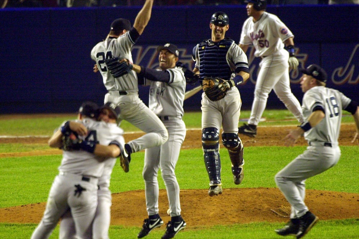 ARCHIVO - El primera base de los Yankees de Nueva York, Tino Martínez (24), salta a los brazos del lanzador Mariano Rivera mientras el receptor Jorge Posada, tercero desde la derecha, Scott Brosius (18) y otros celebran después de derrotar a los Mets de Nueva York en el Juego 5 de la Serie Mundial 4-2 para convertirse en los campeones de la Serie Mundial de 2000, el 26 de octubre de 2000, en el Shea Stadium de Nueva York. (AP Foto/Bill Kostroun, archivo)
