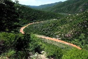 ARCHIVO - El río Sonora, contaminado por un derrame de 10 millones de galones de sulfato de cobre y metales pesados procedentes de la mina de cobre de Buenavista, se abre paso por las montañas cerca de la población de Mazocahui en el estado norteño de Sonora, México, el 12 de agosto de 2014. Residentes del estado de Sonora protestaron el martes 5 de diciembre de 2023 contra lo que consideran constantes demoras de las autoridades en los procesos de limpieza y de reparación de la contaminación de hace casi una década. (AP Foto/El Imparcial, Julián Ortega, Archivo)