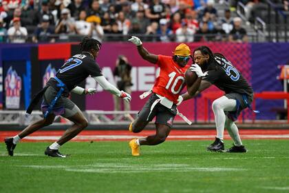 ARCHIVO - El wide receiver Tyreek Hill (10) acarrea el balón ante la marca del cornerback Tariq Woolen (27) y linebacker Za'Darius Smith (55) durante un juego de fútbol bandera durante el Pro Bowl de la NFL, el 5 de febrero de 2023, en Las Vegas. (AP Foto/David Becker)