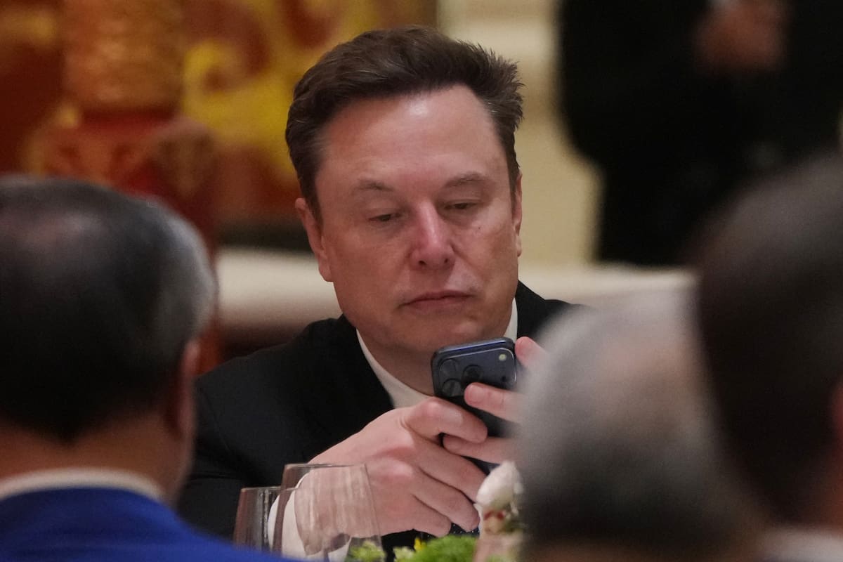 ARCHIVO - Elon Musk utiliza su celular durante una cena de Estado para el presidente de Estados Unidos, Donald Trump, y el de China, Xi Jinping, en el Gran Salón del Pueblo, el 14 de mayo de 2026, en Beijing. (AP Foto/Mark Schiefelbein, archivo)