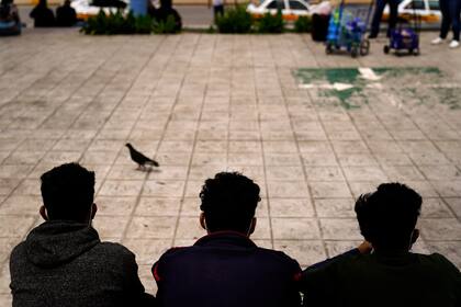 ARCHIVO - En esta foto de archivo del 13 de mayo de 2021, migrantes hondureños se sientan en una plaza en la frontera después de ser devueltos de Estados Unidos a México, en Reynosa, México. (AP Foto/Gregory Bull, Archivo)