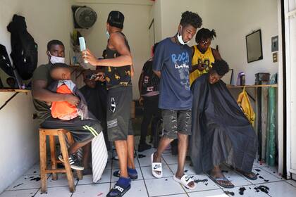 ARCHIVO - En esta foto de archivo del 3 de setiembre de 2021, migrantes haitianos están en una peluquería improvisada en Tapachula, México. Miles de migrantes, en su mayoría haitianos, están varados en la ciudad sureña de Tapachula. Muchos esperan meses, hasta un año, para que procesen sus pedidos de asilo. (AP Foto/Marco Ugarte, File)