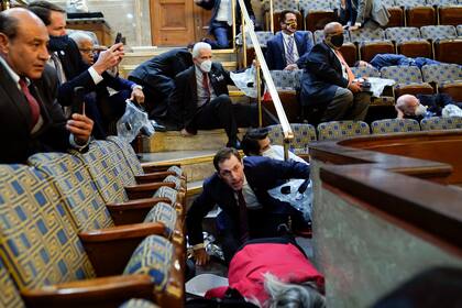 ARCHIVO - En esta foto de archivo del 6 de enero de 2021, gente se refugia cuando los insurrectos tratan de irrumpir en el recinto de la Cámara de Representantes en el Capitolio, Washington. (AP Foto/Andrew Harnik, File)