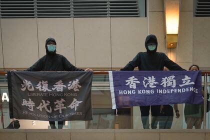 ARCHIVO - En esta foto del 9 de junio, manifestantes muestran una pancarta que dice "Liberar a Hong Kong, Revolución de nuestros tiempos", izquierda; y otra que dice "Independencia para Hong Kong", en un centro comercial durante una protesta en la ciudad.  La policía en Hong Kong arrestó a un hombre de 40 años por sospechas de usar palabras sediciosas luego de que una pancarta de protesta fue vista colgada de su apartamento, dijeron las autoridades el 22 de junio. (AP Foto/Vincent Yu)