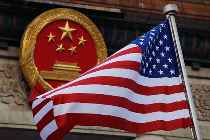 ARCHIVO - En esta foto del 9 de noviembre del 2017, se ve una bandera estadounidense junto al emblema nacional de China en una ceremonia de bienvenida a visitantes estadounidenses. (AP Foto/Andy Wong)