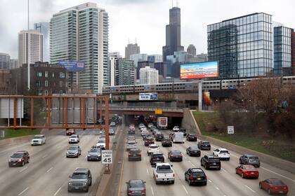 ARCHIVO - En esta fotografía de archivo del 31 de marzo de 2021 se ven vehículos circulando por la autopista interestatal 90 mientras un tren suburbano pasa por la vía elevada en Chicago. (AP Foto/Shafkat Anowar, Archivo)
